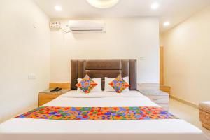 瓜廖尔FabHotel Royal Aanandam的卧室配有一张带彩色枕头的大型白色床。