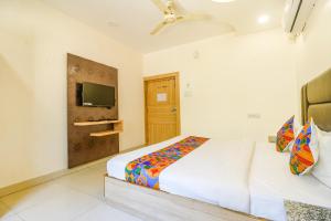 瓜廖尔FabHotel Royal Aanandam的一间卧室设有两张床,墙上配有电视。