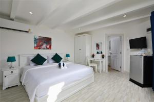 卡塔海滩Kata White Villas的白色的卧室配有一张白色的大床和一张书桌