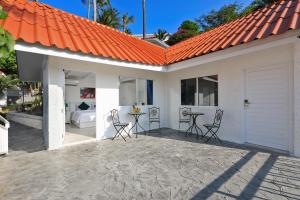 卡塔海滩Kata White Villas的橙色屋顶房屋,配有椅子和桌子