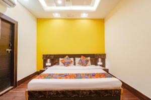 瓜廖尔FabExpress Ambika Dx的一间卧室配有一张黄色墙壁的床