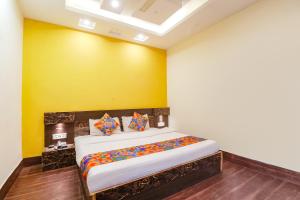 瓜廖尔FabExpress Ambika Dx的一间卧室配有一张黄色墙壁的床