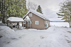 MadawaskaCozy Maine Lakefront Cabin Rental的前面的地面上积雪的房子