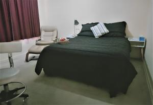 卡尔古利2BR house in West Lamington的一间卧室配有一张黑色的床和一把椅子