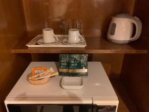 小樽Hotel HANAMIZUKI-Adult Only的架子上装有两盘子和杯子的小冰箱