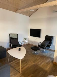 SvinningeDejlig lejlighed的客厅配有两把椅子、一张桌子和一台电视