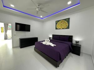 南芭堤雅CHATEAU DALE POOL VILLA 176 nearby WALKING STREET的一间卧室配有一张紫色的床和一台电视机