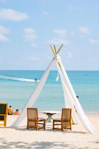 曾蒙海滩湾海滩度假酒店的海滩上的帐篷,配有椅子和桌子