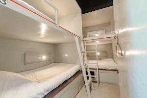 芭堤雅市中心Jurockotel的小型客房设有两张双层床,配有梯子
