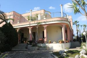 卡斯特里尼亚诺德尔卡波Villa la Bifora by Salento com的一座粉红色的房子,前面有棕榈树
