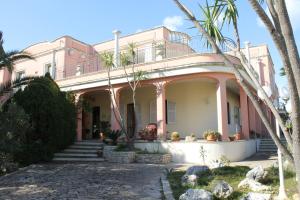卡斯特里尼亚诺德尔卡波Villa la Bifora by Salento com的一座粉红色的房子,前面有棕榈树