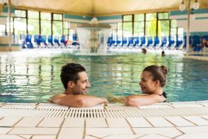 维尔兹Terme Banovci - Hotel Zeleni Gaj的坐在游泳池里的男人和女人