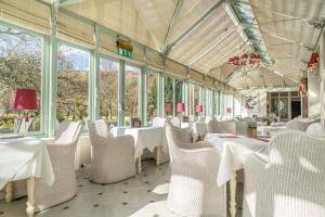 凯西克湖泊区博罗代尔酒店的餐厅设有白色的桌椅和窗户。