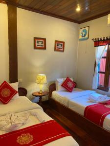 琅勃拉邦苏提考恩1号酒店的一间设有两张床和一盏灯的房间