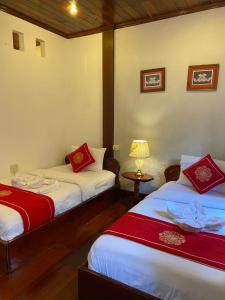 琅勃拉邦苏提考恩1号酒店的客房设有两张床和一张带台灯的桌子。