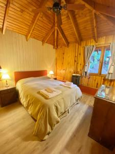 圣马丁德洛斯Villa Cümen的一间带一张大床的卧室,位于一个拥有木制天花板的房间