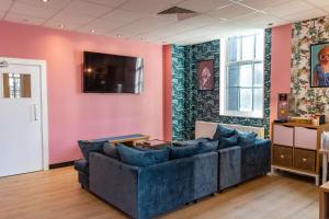 伦敦Hostelle - women only hostel London的客厅配有沙发和粉红色墙壁上的电视
