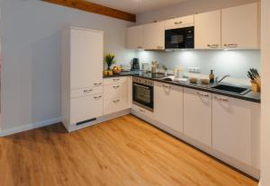 拉策堡Frünn Stuuv的厨房配有白色橱柜和硬木地板。