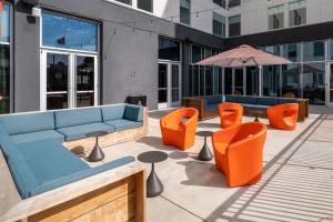 奥斯汀Aloft Austin South的天井配有沙发、橙色椅子和遮阳伞