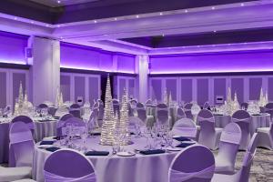 利兹万豪利兹度假酒店的舞厅配有白色桌椅和紫色照明