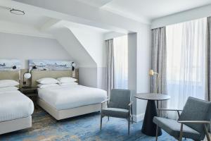 伯恩茅斯万豪伯恩茅斯高崖酒店的酒店客房带两张床和一张桌子以及椅子。