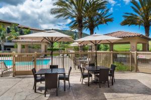 圣路易斯-奥比斯保圣路易斯-奥比斯保万怡酒店的游泳池旁带桌子和遮阳伞的天井