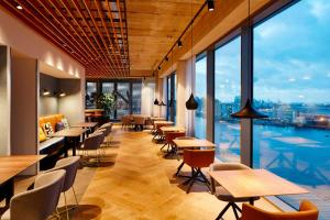 阿姆斯特丹阿姆斯特丹木材港万豪原住客栈的餐厅设有桌椅和大窗户。