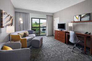 科里奥波利斯Courtyard by Marriott Pittsburgh Airport的酒店客房设有一张沙发和一张带电视的书桌。