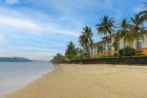 帕纳吉果阿万豪Spa度假酒店的棕榈树和海洋海滩上的酒店