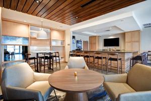 普里茅斯Fairfield Inn & Suites by Marriott Plymouth的一间带桌椅的客厅和一间厨房