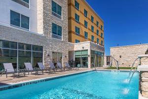 休斯顿Fairfield Inn & Suites Houston Memorial City Area的一座带椅子的游泳池以及一座建筑