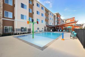 汤博尔Residence Inn by Marriott Houston Tomball的大楼前带游乐场的游泳池