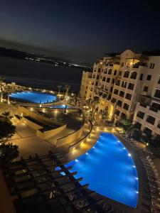 索瓦马Samarah Resort D44的城市的一座大型游泳池,晚上有蓝色的灯光