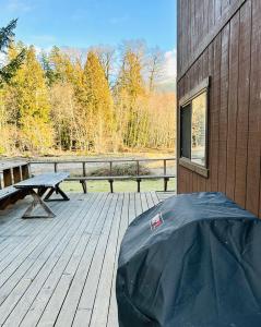帕克伍德Waterfront Cabin at White Pass and Mount Rainier National Park的木甲板上设有野餐桌和长凳
