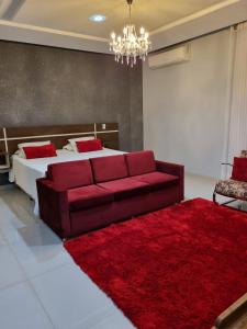 维列纳Hotel e Locadora Vizon的一间卧室配有红色的沙发,另一张床铺有红色地毯。