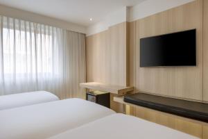 科尔多瓦AC Hotel Córdoba by Marriott的酒店客房设有两张床和一台平面电视。