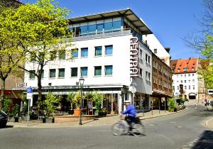 纽伦堡中央酒店的骑着自行车沿着建筑前的街道骑行的人