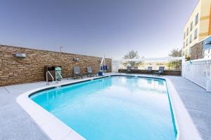 凤凰城Fairfield Inn & Suites by Marriott Phoenix West/Tolleson的一座带椅子的游泳池以及一座建筑
