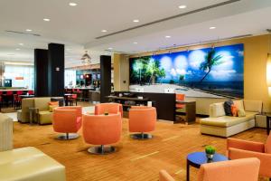 霍姆斯泰德迈阿密家园万怡酒店的酒店大堂设有橙色椅子和大型壁画