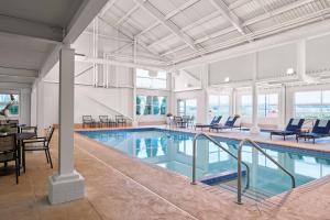 Menomonee FallsDelta Hotels by Marriott Milwaukee Northwest的一个带椅子和桌子的大型室内游泳池