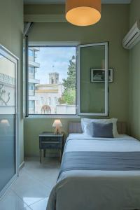 雅典Kimon Hotel Athens的一间卧室设有一张床和一个大窗户