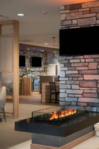 埃德蒙顿Fairfield by Marriott Edmonton International Airport的客厅设有壁炉,砖墙上配有电视
