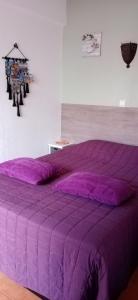 塔维拉le Boucanier的卧室内的紫色床和紫色棉被