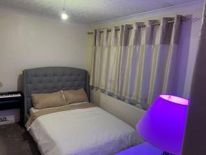 博勒姆伍德Lovely 3 bedroom house in Borehamwood .的一间卧室配有一张床和紫色灯