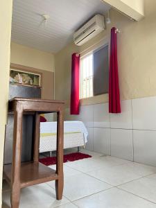 贝贝里比Cantinho Morro Branco的一间设有床铺和红色窗帘的窗户的客房