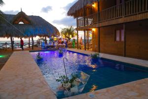 托卢Awa de Mar Playa的一座带游泳池的度假村,周围的人都坐在游泳池旁