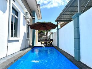 马六甲Bandar Melaka Family Bungalow Private Pool BBQ WiFi Netflix的一座房子旁带遮阳伞的游泳池