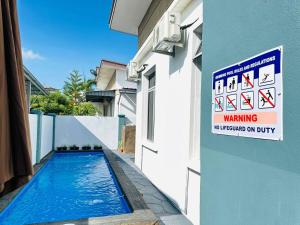 马六甲Bandar Melaka Family Bungalow Private Pool BBQ WiFi Netflix的一座游泳池,在建筑物的一侧有标志