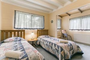 温特沃斯瀑布阿卡迪亚小屋的一间卧室设有两张床、一把椅子和窗户。