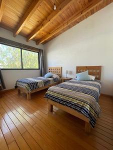 特基斯基亚潘Casa Angeles Centro de Tequisquiapan para 6 personas的铺有木地板的客房内的两张床